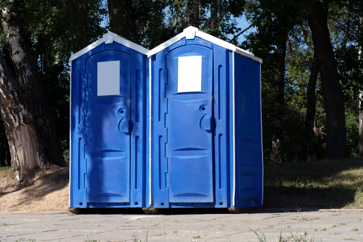 Two portable toilets placed on the ground, providing sanitation facilities in an outdoor environment.